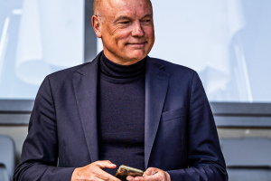 AGF's cheftræner Uwe Rösler smiler tilfreds med sin mobiltelefon i hænderne