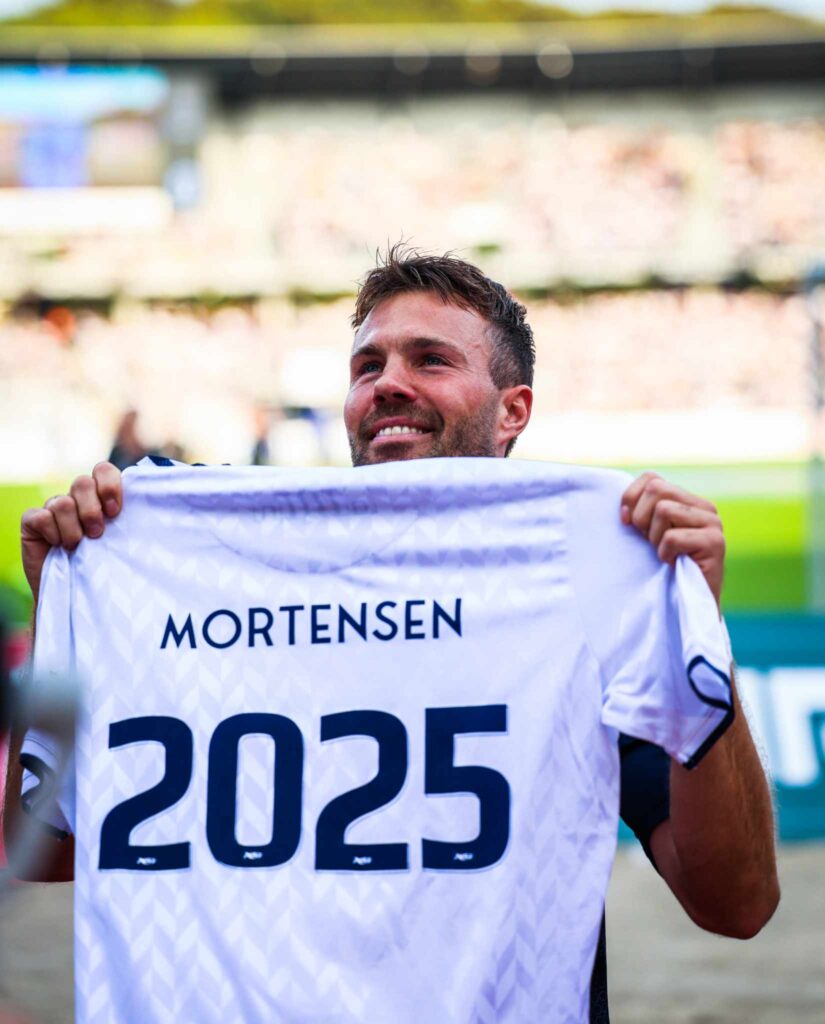 Patrick Mortensen fremviser en trøje med teksten "Mortensen 2025", efter offentliggørelsen af sin kontraktforlængelse