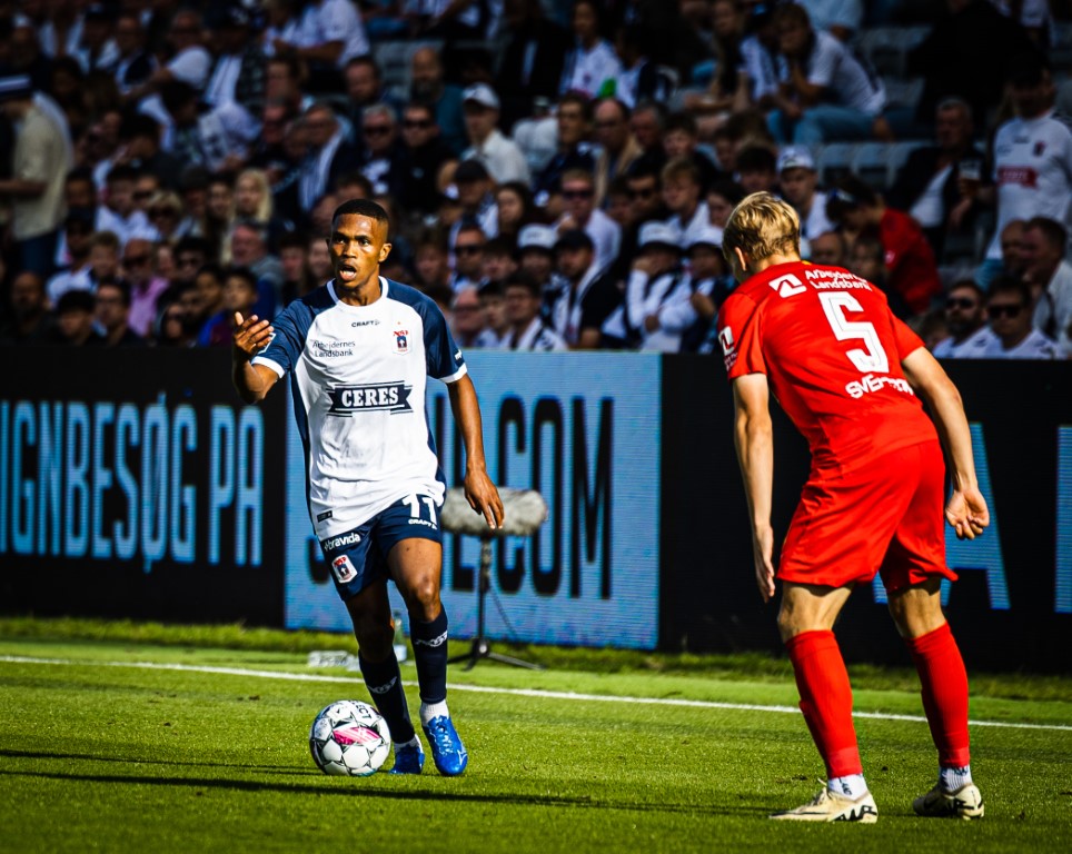 Gift Links gestikulerer med højrehånd, mens han med publikums øjne hvilende på sig udfordrer en FC Nordsjælland-spiller på Ceres Park.